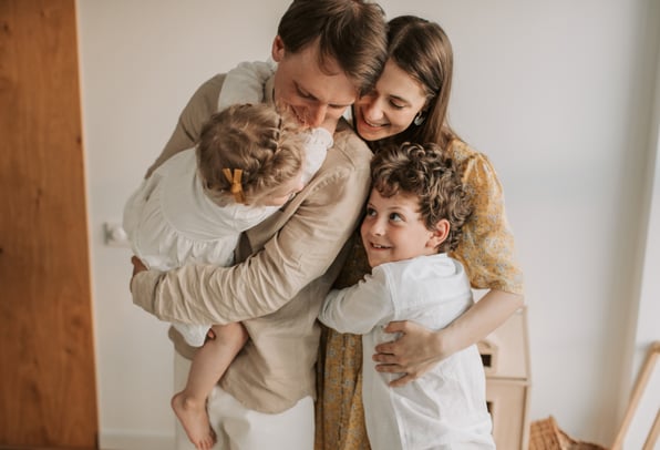 Parents hugging their kids as they celebrate achieving financial stability. 