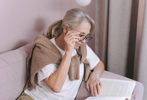 Older woman reviewing financial documents at home, representing understanding pension advice fees and financial planning in the UK.