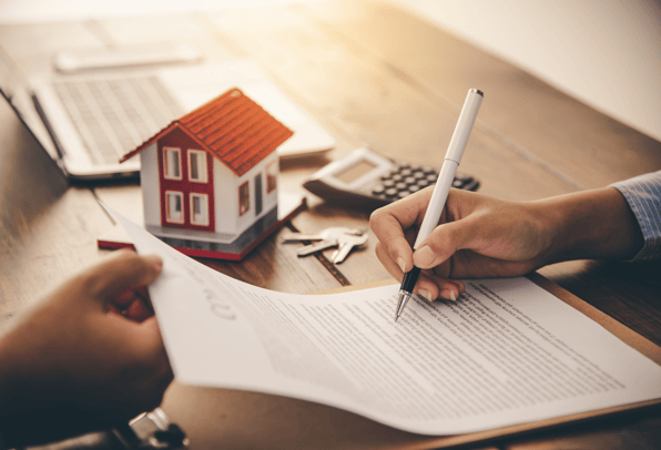 A young woman signing a mortgage after talking to a Financial Adviser who helped her climb the housing property ladder.
